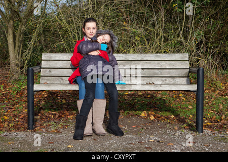Zwei Schwestern kuscheln auf Parkbank Stockfoto