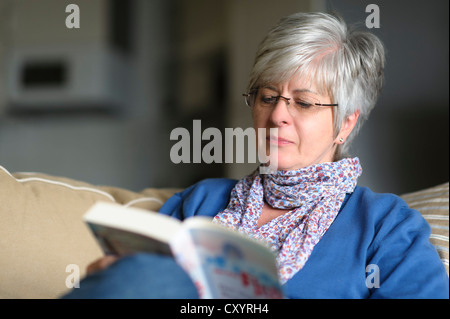 Frau sitzt auf dem Sofa ein Buch zu lesen Stockfoto