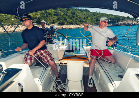 Drei Männer eine Segelcrew am Heck einer Yacht bei einem Segeln Manöver abseits die kroatische Küste, Kroatien, Europa Stockfoto