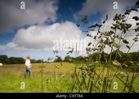 Young woman walking in countryside with wild grass in foreground Stockfoto