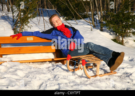 Frau, 35 Jahre, sitzen auf einer Bank, wobei in der Wintersonne auf Mt Kickelhahn bei Ilmenau, Thüringen Stockfoto