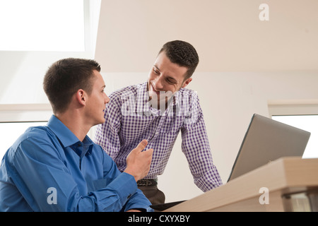 Zwei junge Kolleginnen und Kollegen, die gemeinsam auf einem computer Stockfoto