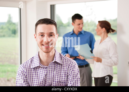 Porträt eines lächelnden jungen Mannes vor Kollegen Stockfoto