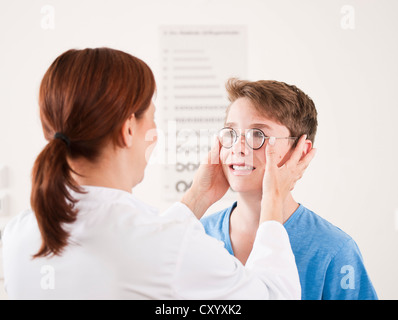 Augenarzt ein Teenager Brille aufsetzen Stockfoto