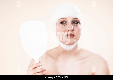 Frau mit Markierungen auf ihrem Gesicht, Blick in den Spiegel vor einer plastischen Operation Stockfoto