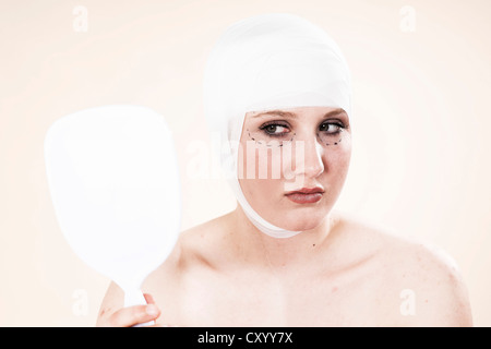 Frau mit Markierungen auf ihrem Gesicht, Blick in den Spiegel vor einer plastischen Operation Stockfoto