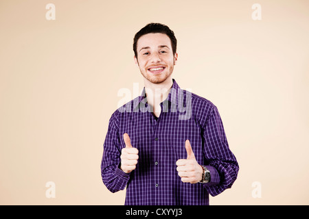 Junger Mann, ein Daumen-hoch-Geste mit beiden Händen Stockfoto