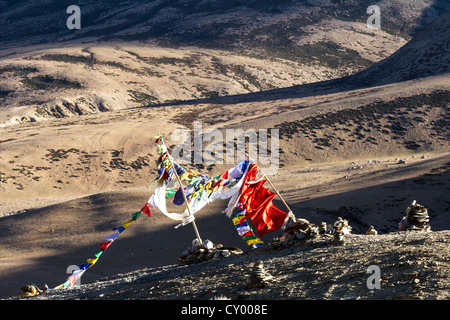 Buddhistische Gebetsfahnen im Wind gegen die Berge auf den Sonnenuntergang (Nordindien) Stockfoto
