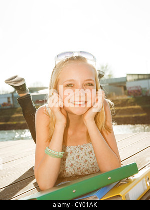 Lächelndes Mädchen liegend auf einem Holzsteg Stockfoto