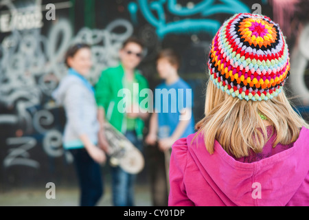 Jugendliche stehen vor einer Wand mit Graffiti, eine Mädchen stehen im Vordergrund Stockfoto