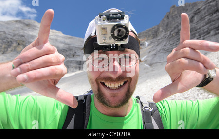 Junger Mann montiert Berg Wanderer mit einer GoPro HD Videokamera nach seinem Kopf, Karwendel Mountains National Park, Tirol, Österreich Stockfoto