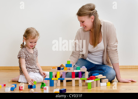 Kleine Mädchen und junge Frau, die Spaß spielen mit Bauklötzen auf dem Boden Stockfoto