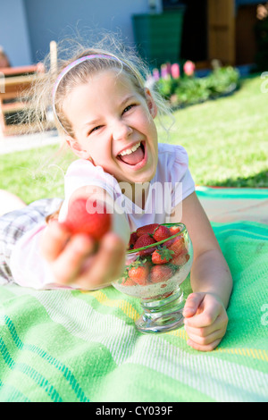 Lachende Mädchen mit Erdbeeren im Garten Stockfoto