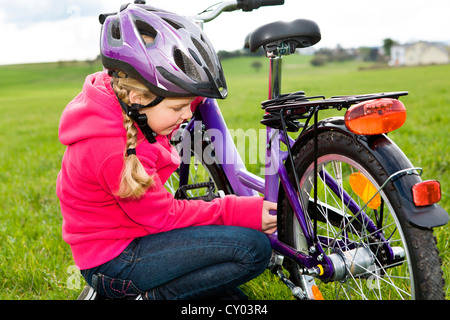 Mädchen tragen einen Helm, überprüfen ihr Fahrrad Stockfoto