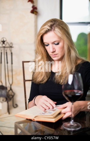 Kaukasischen Frau in ihren 30ern, lesen Sie ein Buch bei einem Glas Rotwein Stockfoto