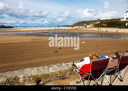 Älteres Ehepaar in Liegestühlen mit Blick auf das Meer auf die Küste in Perranporth Perrenporth, Cornwall, UK, England Stockfoto