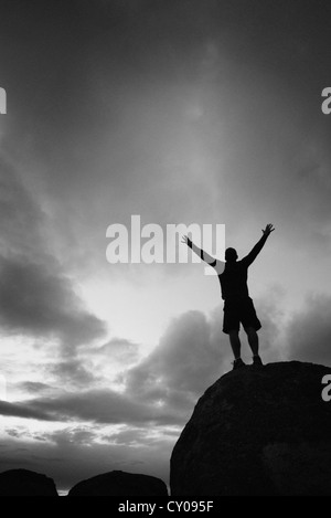 Männliche Figur stehend mit Armen angehoben auf Felsen in der Feier Stockfoto