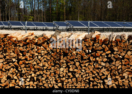 Gestapeltes Brennholz, große Photovoltaikanlage auf einer ehemaligen Mülldeponie auf der Rückseite, abgeschlossen im April 2012 Stockfoto