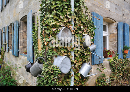 Zink-Wannen und Gießkannen auf einem Efeu bewachsenen alten fränkischen Haus, Simonshofen, Middle Franconia, Bayern Stockfoto