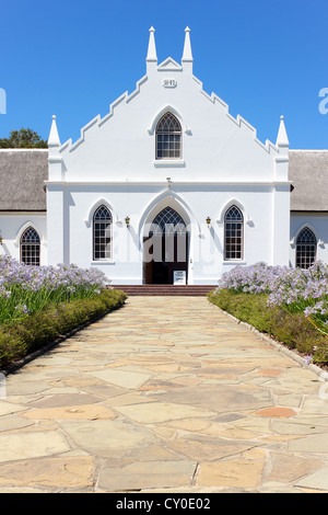 Weiße Kirche in Franschhoek vor blauem Himmel mit steinernen Weg Stockfoto