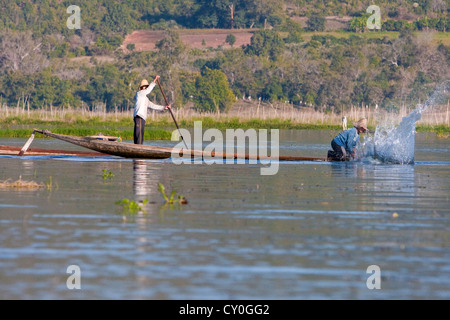 Myanmar, Burma. Fischer schlug das Wasser mit seinem Paddel, um Fische zu betäuben. Inle-See, Shan-Staat. Stockfoto