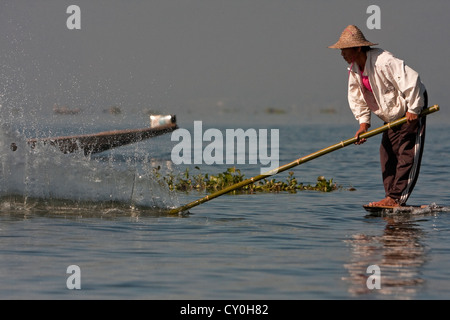 Myanmar, Burma. Fischer schlug das Wasser mit einem Bambusstab, Fische zu betäuben. Inle-See, Shan-Staat. Stockfoto