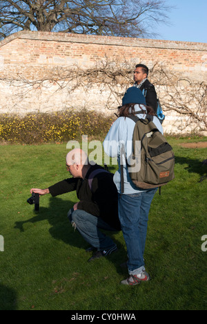 Mann nach unten um zu fotografieren mit anderen Menschen stand neben ihm hocken Stockfoto