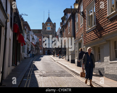 Eine ältere Frau mit ihrem Korb geht auf der steilen Straße zu den Geschäften auf Lion Street, Rye, Sussex Stockfoto