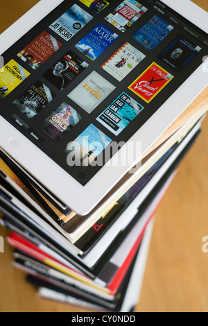 iPad Tablet-Computer mit kindle e-Book-Bibliothek-Anwendung und Haufen von traditionellen Hardcover Bücher Stockfoto