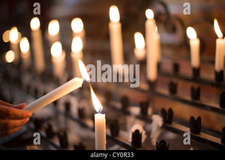 Frau Licht Gebet Kerze aka anbieten, Opfer oder Denkmal Kerzen in einer Kirche Stockfoto