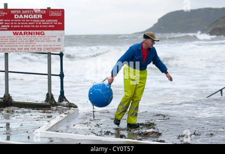 Ein Arbeiter des Swansea Rates ruft eine Boje aus den Trümmern gespült, bei Flut in den rauen Gewässern vor Caswell Bucht in der Nähe von Swansea Stockfoto