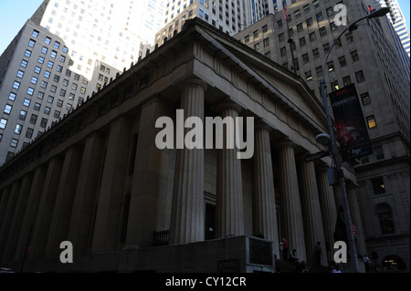 Sonnenschutz Wolkenkratzer erhebt sich über Neo-klassischen Federal Hall National Memorial, Wall Street in Nassau Street, New York Stockfoto