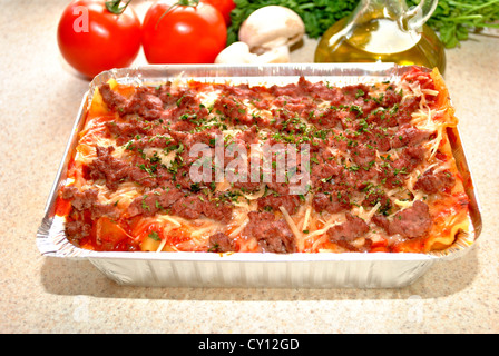 Cheeseburger-Lasagne mit Zutaten im Hintergrund Stockfoto