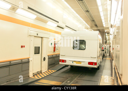 Auto und Anhänger Wohnwagen in einem Zug Wagen eines Eurotunnel Le Shuttle Reisen durch den Kanaltunnel. Stockfoto
