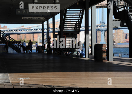 Sonne Schatten Blick auf Manhattan Bridge, Metall Treppen, Menschen entspannen wharf, Pier 17, South Street Seaport, New York Ende Stockfoto