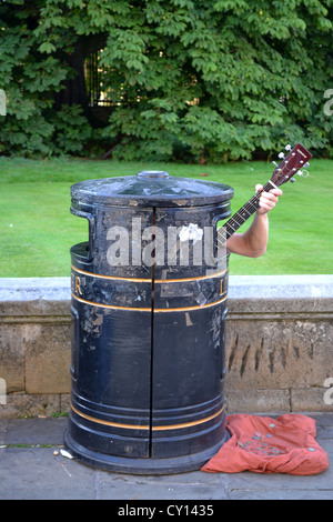 Busker / Street Performer in Mülltonne singt und spielt Gitarre, Trumpington St, Cambridge, England. Stockfoto