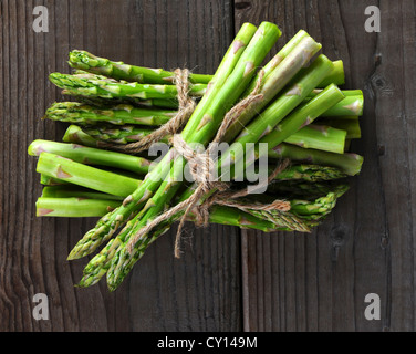 Trauben von Spargel mit Bindfaden auf Holz Hintergrund gebunden. Draufsicht im Querformat. Stockfoto