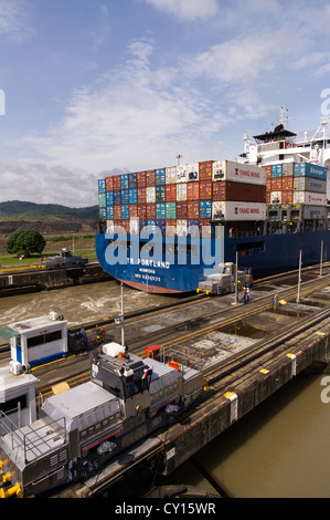 Panama Panama-Kanal Containerschiff YM Portland Transite die Pedro Miguel Schleusen des Panama-Kanals mit Hilfe der elektrischen Pantoletten Stockfoto