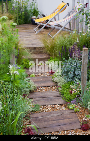 Extensive Begrünung von Gräsern geschmückt Holz Terrasse und über die geschwungene Rückwand Stockfoto