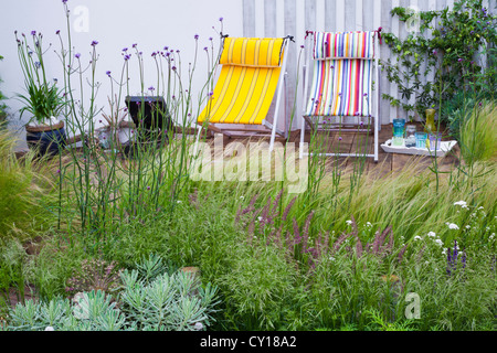 Extensive Begrünung von Gräsern geschmückt Holz Terrasse und über die geschwungene Rückwand Stockfoto