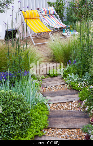 Extensive Begrünung von Gräsern geschmückt Holz Terrasse und über die geschwungene Rückwand Stockfoto