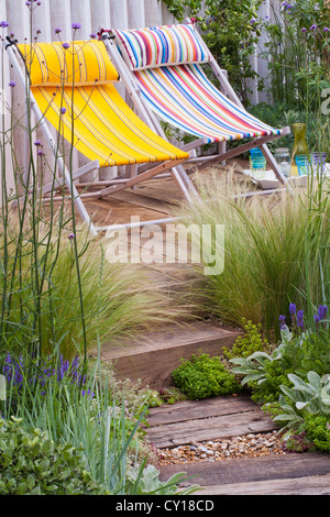 Extensive Begrünung von Gräsern geschmückt Holz Terrasse und über die geschwungene Rückwand Stockfoto