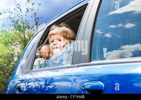 niedliche kleine Junge im Auto unterwegs und Naturbeobachtung durch offene Fenster Stockfoto