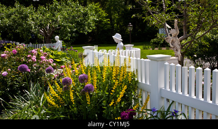 Bunte Frühlingsblume Gartengrenze, gelbe Carolina Lupin, Allium Globe und ein weißer Picket-Zaun-Garten in New Jersey, USA, False Indigo Baptizia Stockfoto