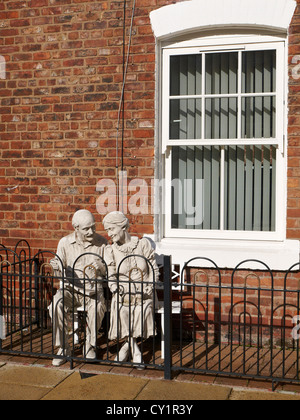 Statue von Ehepaar im Ruhestand sitzen auf einer Bank an der Vorderseite eines Privathauses in Ancoats Manchester UK Stockfoto