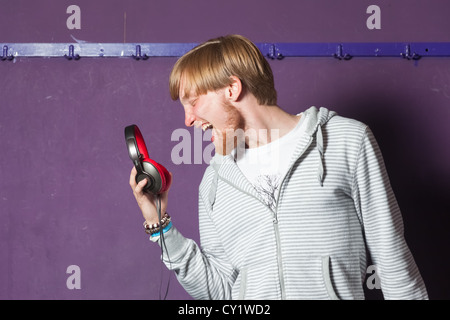 Junger Mann singen, seine Kopfhörer an kühlen Ort Stockfoto