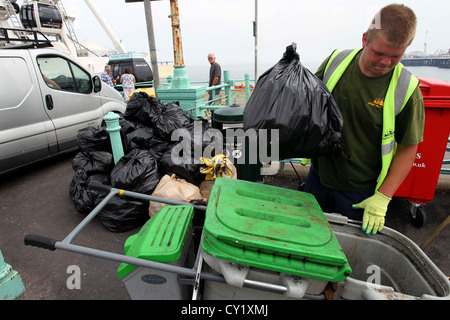 Ein Rat Binman Abholung der Müll von Brighton Beach in der Nähe der Pier von Brighton (Palast), East Sussex, UK. Stockfoto