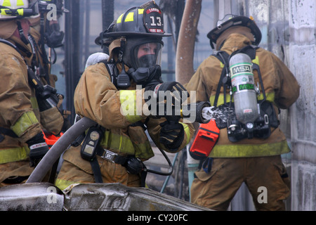 Eine Frau Feuerwehrmann aus Lannon Feuerwehr ein Feuer Wasser aufsetzen Stockfoto