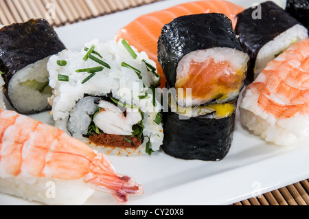 Gemischte Sushi-Rollen auf einer Platte mit Bambus im Hintergrund Stockfoto