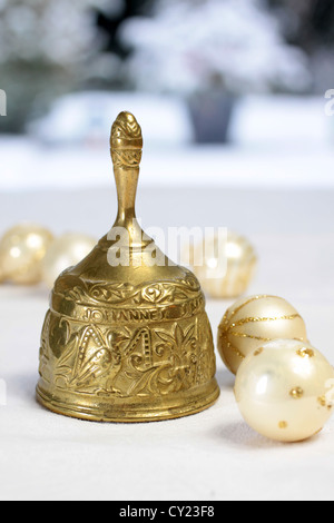 Goldene Weihnachten Bell und Weihnachtskugeln vor Schnee bedeckten Terrasse Stockfoto